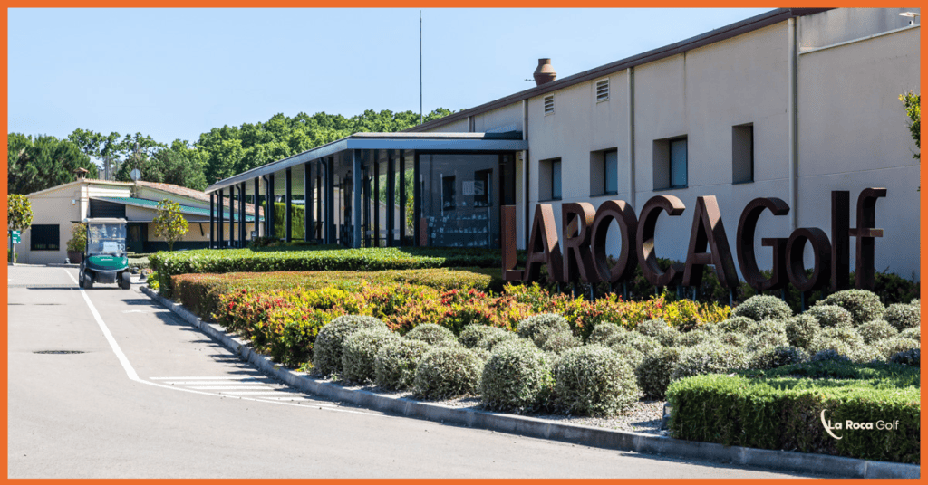 Entrada del clubhouse de La Roca Golf con el logotipo grande y jardines bien cuidados, ubicado en La Roca del Vallès, Barcelona