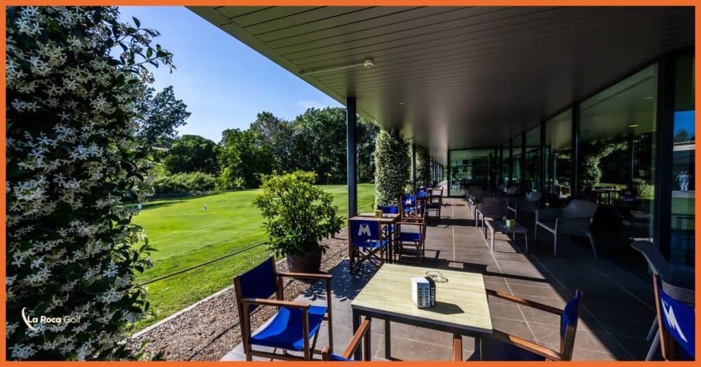 Terraza del clubhouse de La Roca Golf con vista al campo de golf, mesas al aire libre y vegetación rodeando el área, en La Roca del Vallès, Barcelona