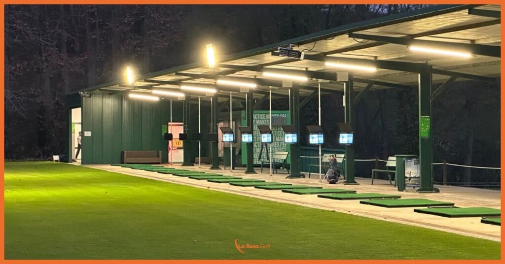 Centro de entrenamiento iluminado La Roca Golf con tecnología Toptracer, mostrando 8 puestos equipados con pantallas inteligentes, sistema LED de última generación y zona de práctica con césped natural para entrenamiento nocturno en Barcelona