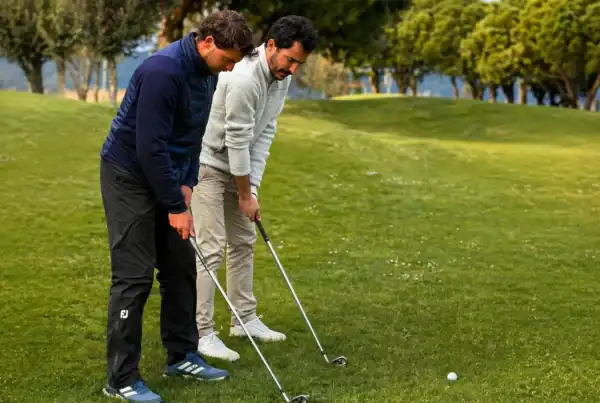 Profesional de golf enseñando la postura del swing a un alumno principiante en La Roca Golf