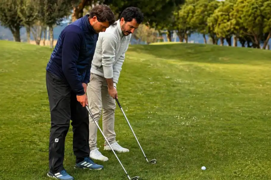 Profesional de golf enseñando la postura del swing a un alumno principiante en La Roca Golf