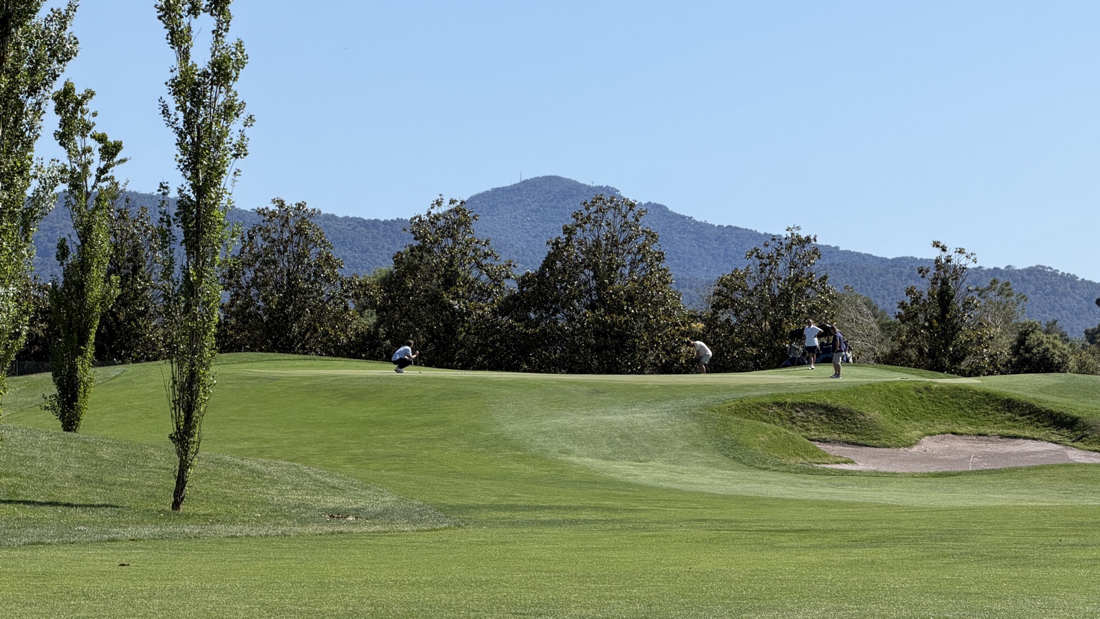 Green on the flat, open course at La Roca Golf with the Montseny behind