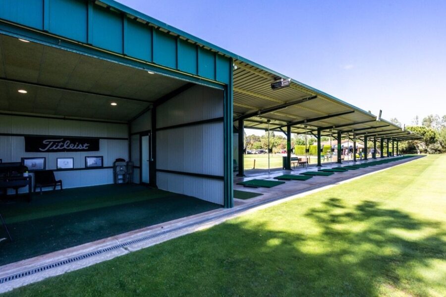 Rangée de postes couverts du practice de La Roca Golf avec les tees en gazon synthétique et le studio d'analyse