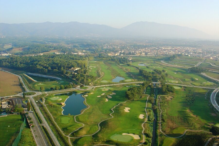 Aerial view of La Roca Golf with the town and mountains behind, an ideal course for weekend golf in Barcelona