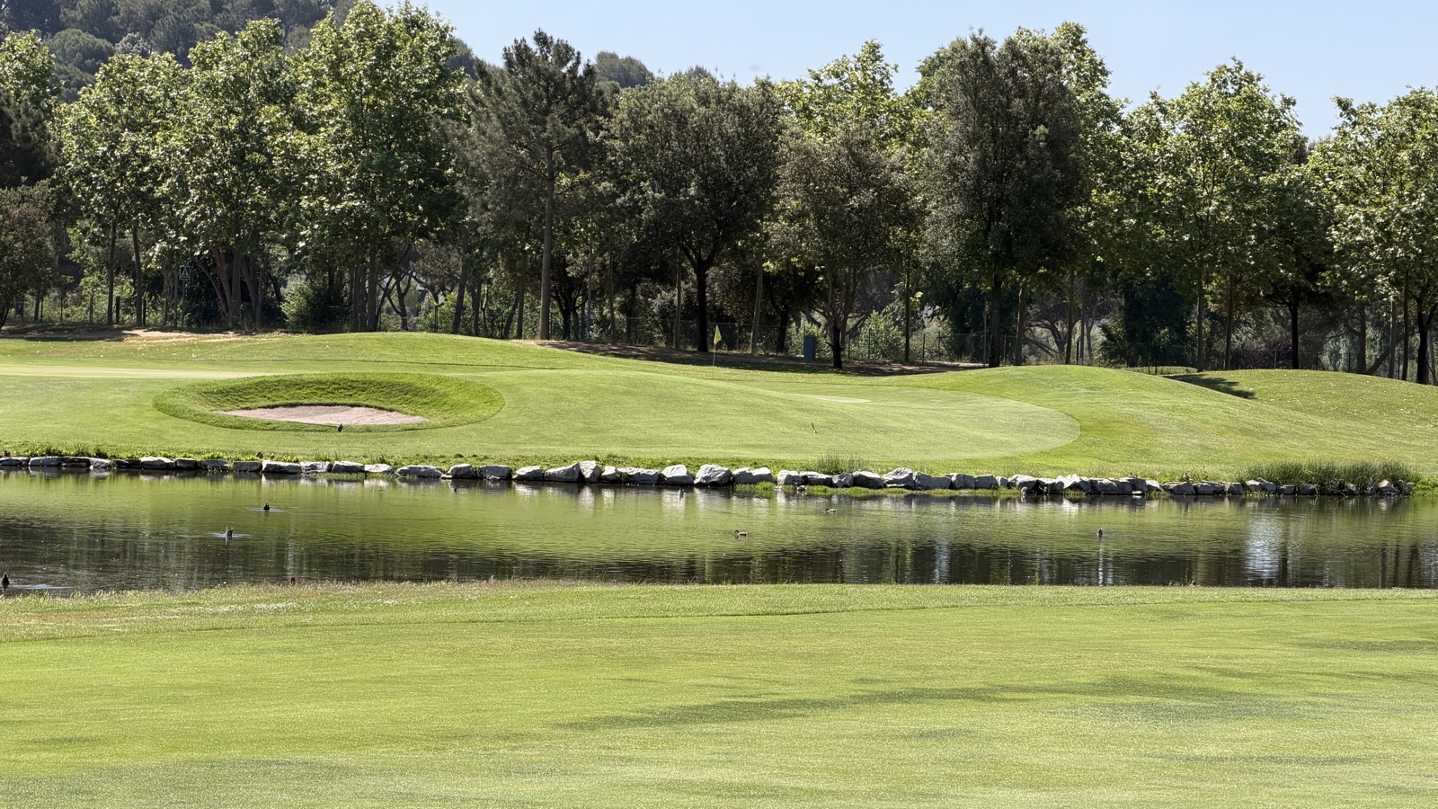 Green de La Roca Golf al costat d'un llac amb bunker, escenari del dia 1 d'un cap de setmana de golf