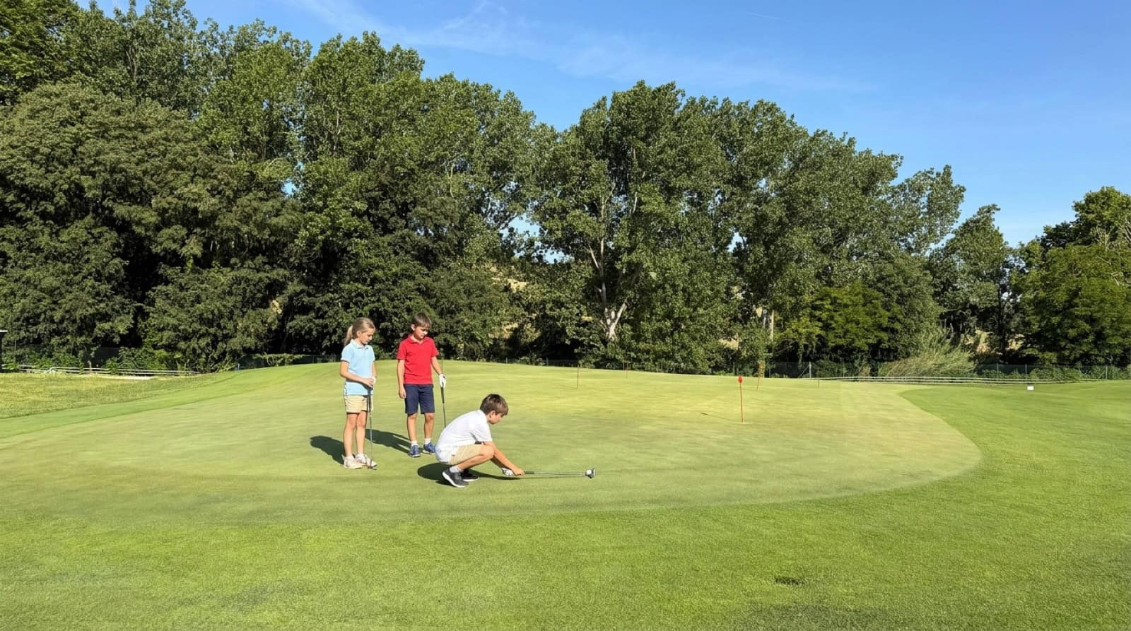 Nens jugant al putt al green de pràctiques de La Roca Golf