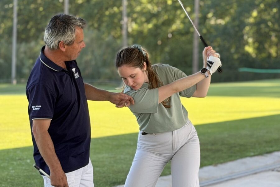 Professor corregint la posició del braç a una alumna al driving range de La Roca Golf, un dels remeis als errors habituals al golf