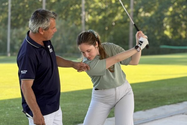 Coach correcting a student's arm position on the driving range at La Roca Golf, the fix for one of the most common golf mistakes