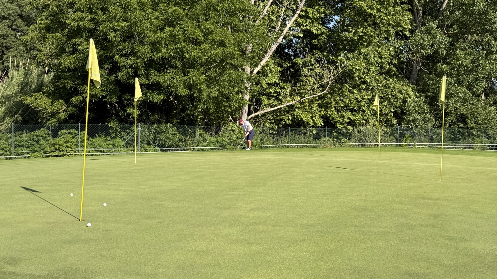 Green d'entraînement de La Roca Golf avec des drapeaux jaunes et un joueur qui travaille son petit jeu