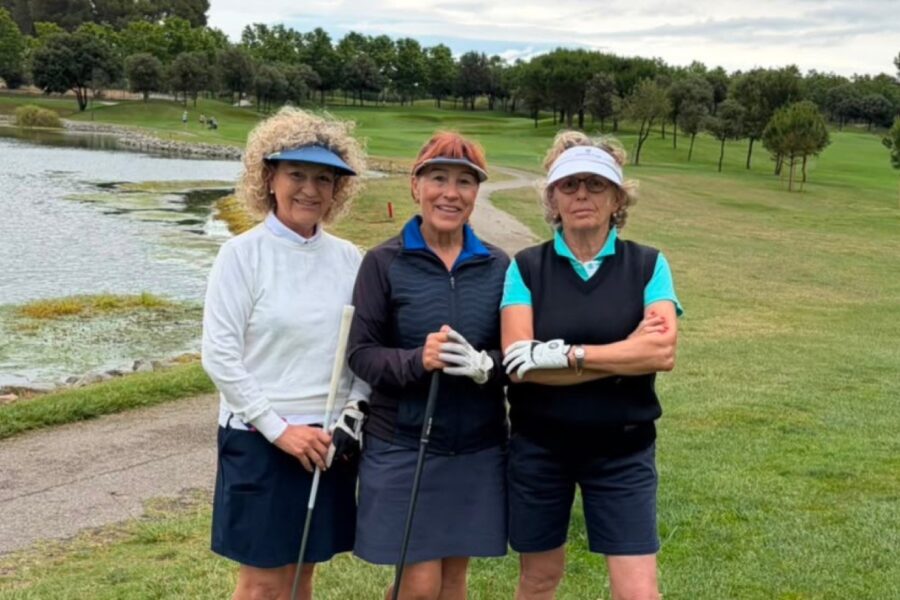Three Swing i Dones players beside one of the lakes at La Roca Golf, with the fairway and treeline behind them.