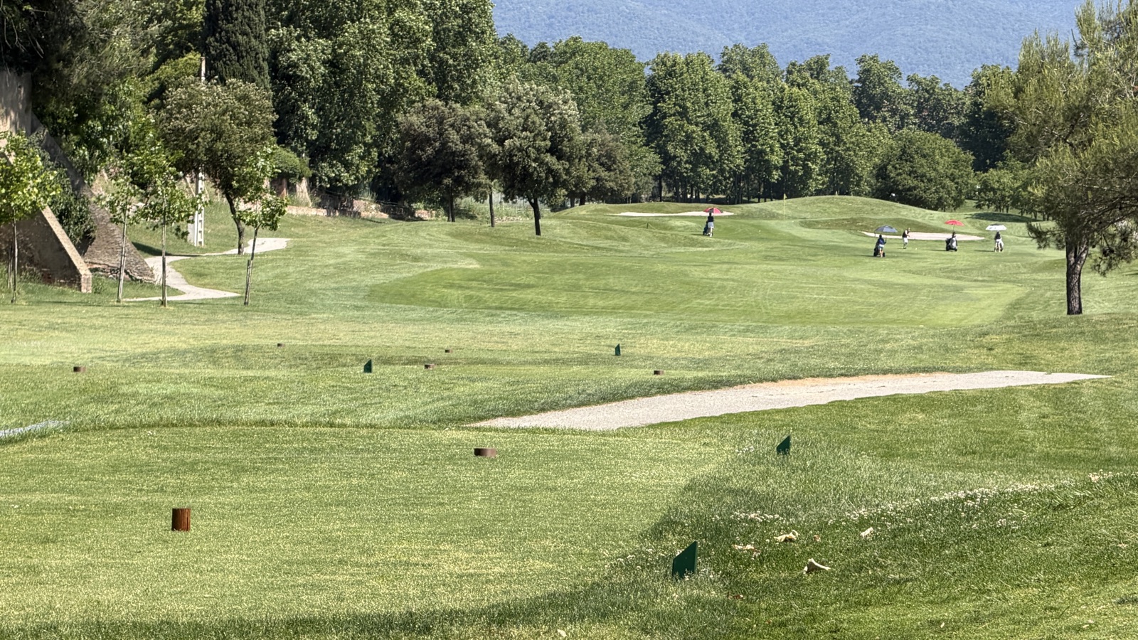 Vue depuis la zone de départs du trou 11 de La Roca Golf vers le fairway, avec un groupe de joueurs qui marchent