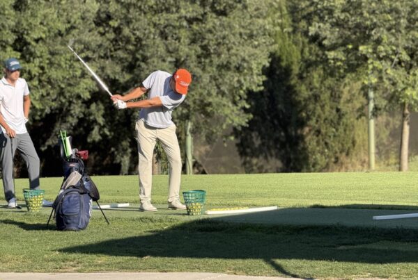 Golfeur travaillant son swing sur le practice de La Roca Golf, avec des paniers de balles et un autre joueur qui observe.