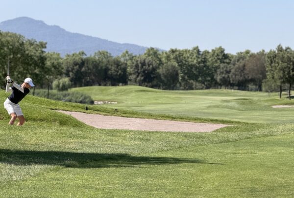Jugador ejecutando un golpe desde la hierba alta junto a un bunker de calle en La Roca Golf.