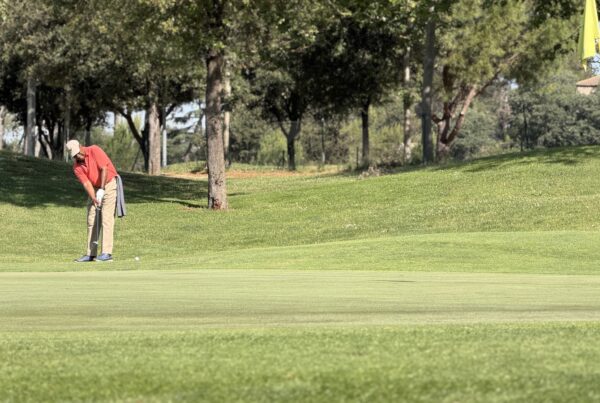 Jugador executant un putt en un green de La Roca Golf amb la bandera groga a la dreta.