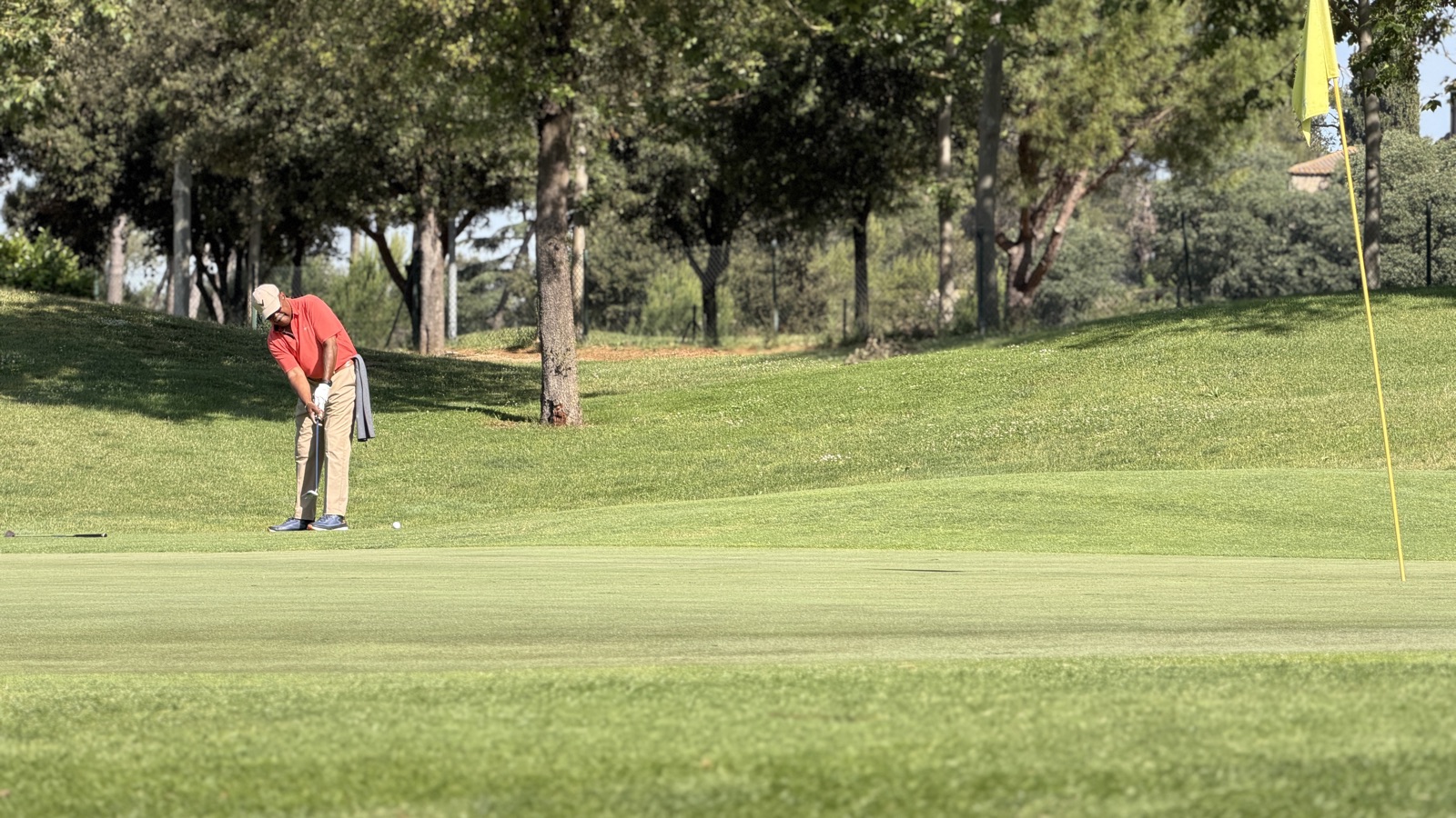 Un joueur exécutant un putt sur un green de La Roca Golf, le drapeau jaune sur la droite.