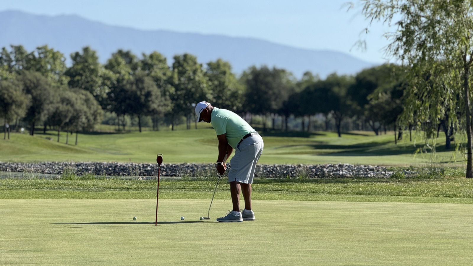 A golfer putting on a green at La Roca Golf, with the fairways of the course behind.