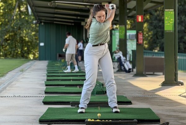 Jugadora al punt més alt del swing en un lloc cobert del Driving Range de La Roca Golf