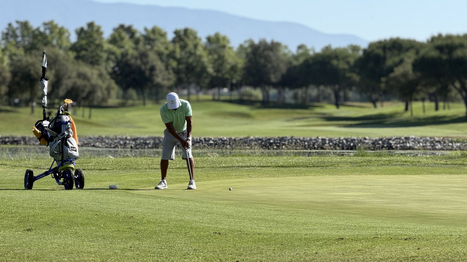 Golfeur avec son chariot jouant un putt sur un green de La Roca Golf